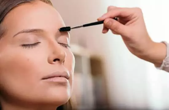 A beautican applying eyebrow makeup to a client's face