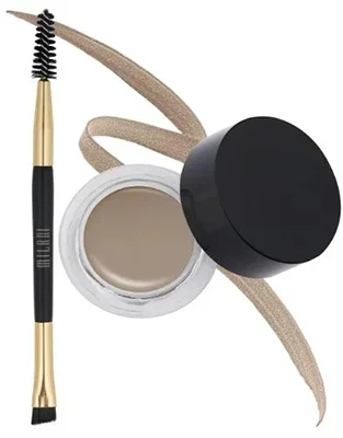 A close-up view of Milani Stay Put Brow Color in Dark Brown showcasing a jar of brow cream beside a brow brush with a spoolie end.