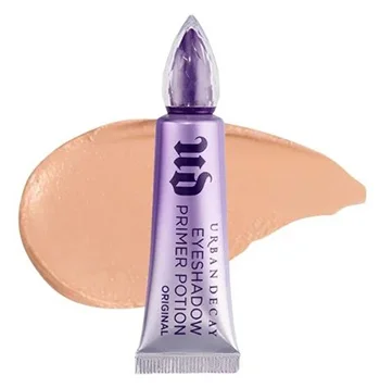 
A tube of Urban Decay Eyelid Primer with a metallic finish surrounded by a swatch of the product in a creamy, light brown shade.