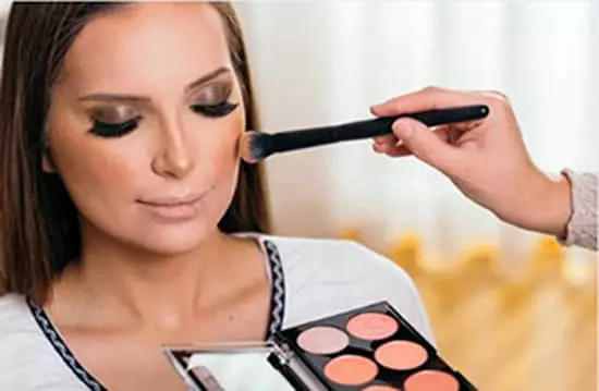 A woman having highlighter applied to her face.